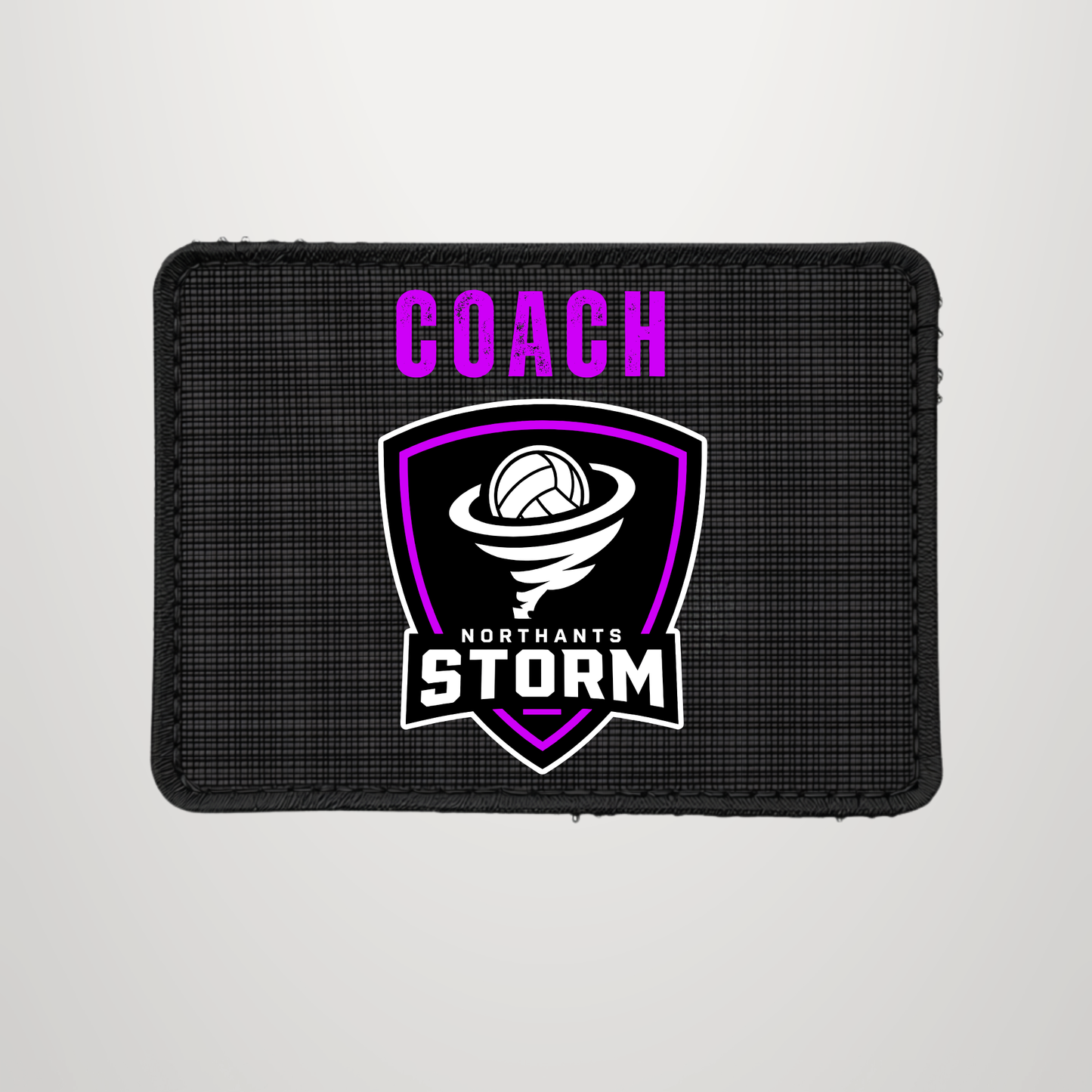 A rectangular black textured patch with a stitched border, featuring the word 'COACH' in bright pink above a shield logo with a volleyball and the words 'NORTHANTS STORM' in white and pink.