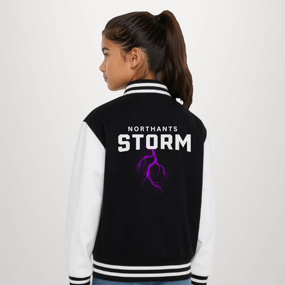 A girl shown from the back wearing a varsity-style jacket with black body panels, white sleeves, and a purple lightning graphic with the text 'NORTHANTS STORM' on the back.