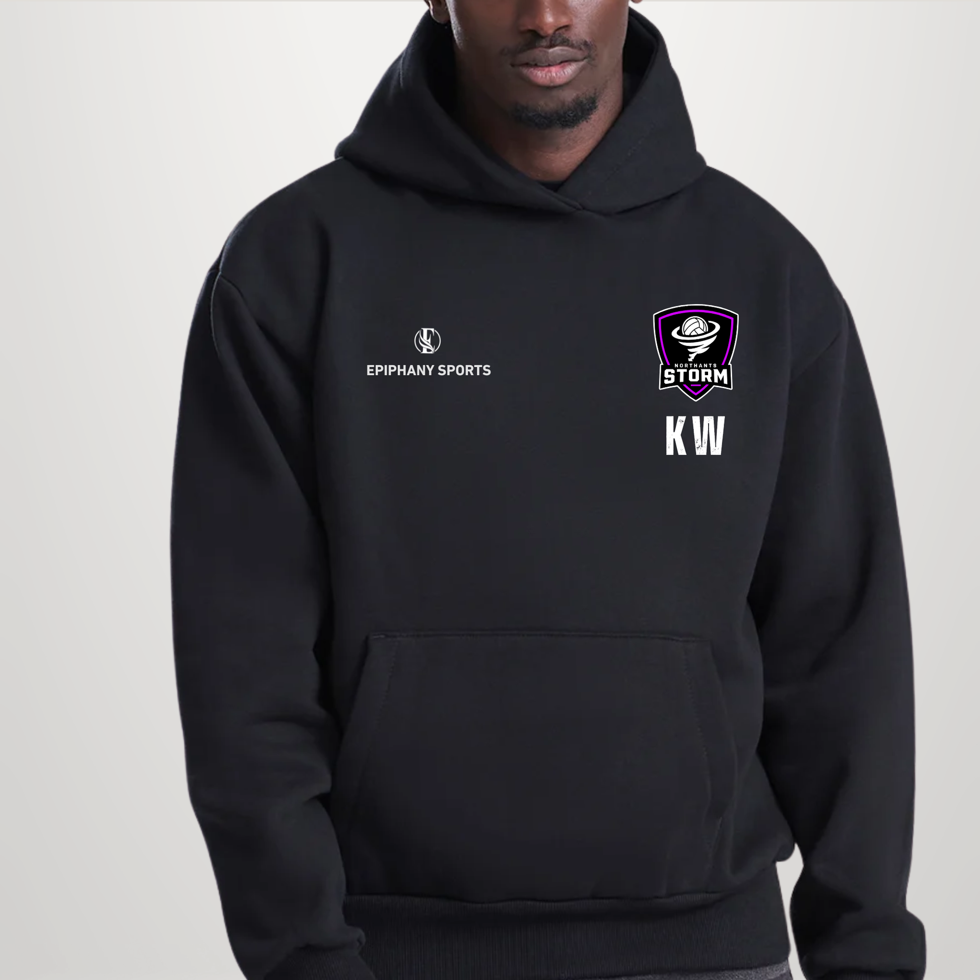 A man wearing a black pullover hoodie with white and purple graphics. The hoodie features the 'EPIPHANY SPORTS' logo on the right chest and a purple 'STORM KW' shield logo on the left chest, set against a plain light grey background.