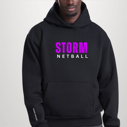 A man wearing a black pullover hoodie with 'STORM' in bright pink and 'NETBALL' in white printed on the chest, set against a plain light gray background.