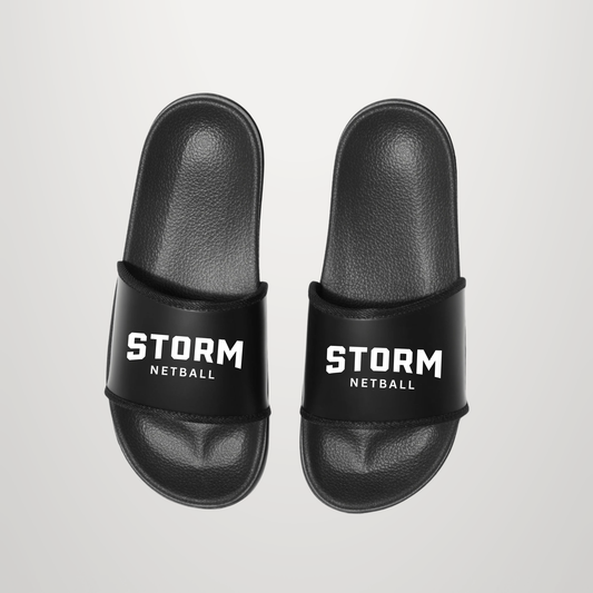 A pair of black slide sandals with 'STORM NETBALL' printed in white on the straps, shown from a top-down view on a light gray background.