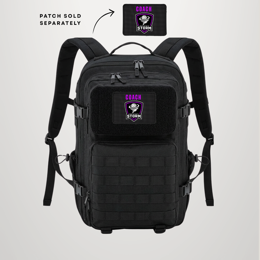 A black tactical backpack shown from the front on a light gray background, with a separate embroidered patch inset at the top right labeled 'PATCH SOLD SEPARATELY' and an arrow pointing to it. The backpack has a front zip pocket with a matching black patch that reads 'COACH STORM' in purple and white.